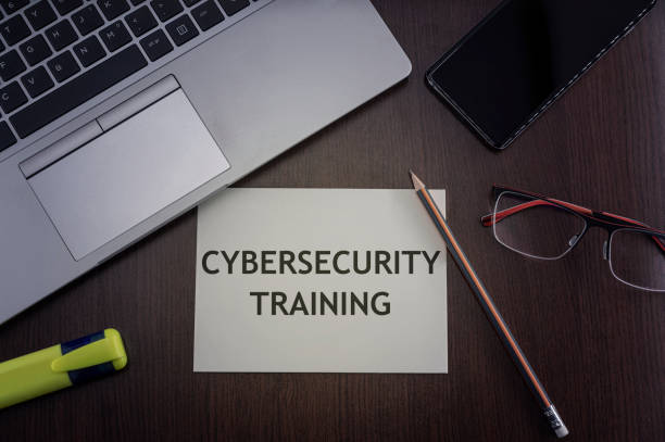 Top view of laptop, phone, glasses and pencil with card with inscription cybersecurity training.